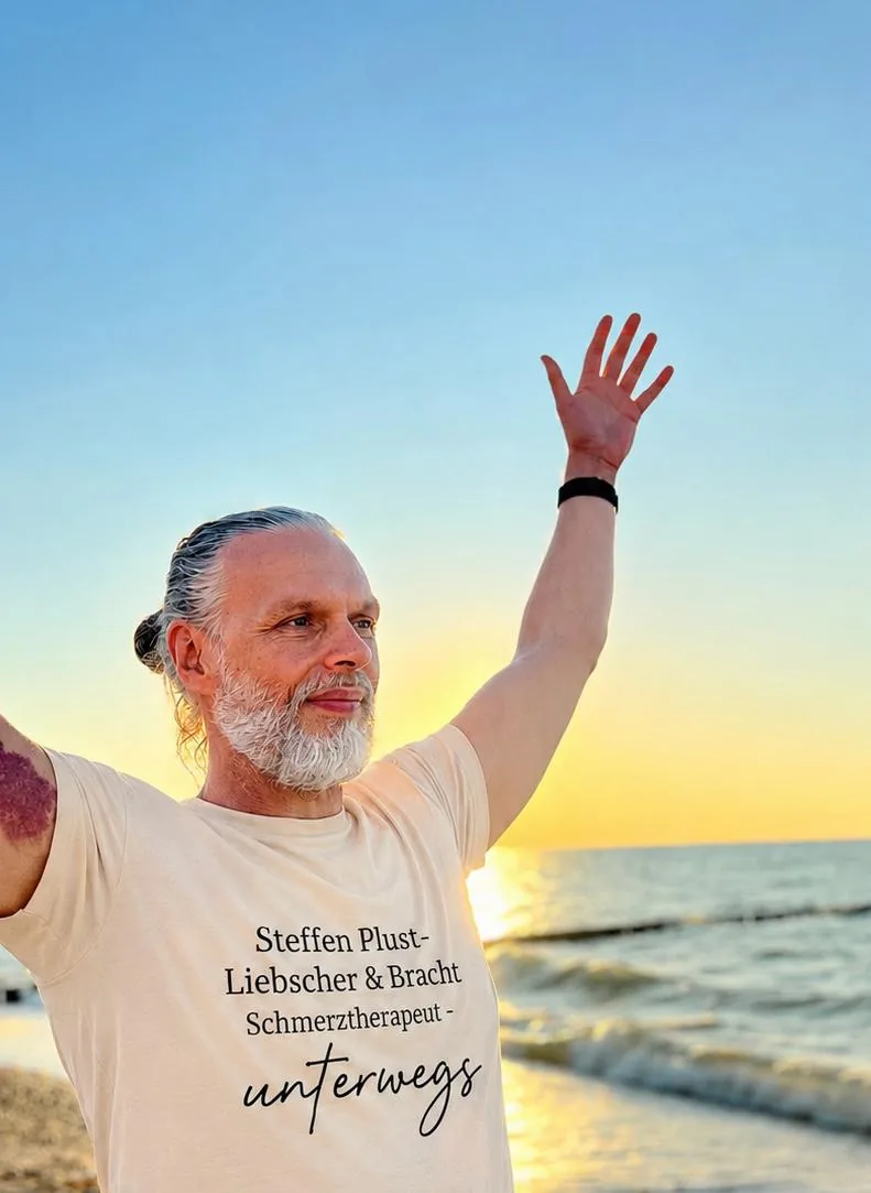 Steffen Plust zeigt eine freie Schulterbewegung am Meer